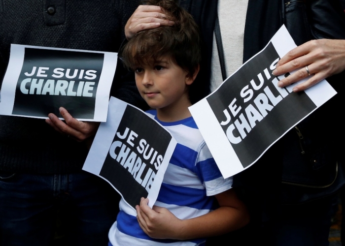 A boy joins supporters of French satirical magazine Charlie Hebdo as they hold photocopies that read 'I am Charlie' during a silent protest outside the Foreign Correspondent Club in Hong Kong, China, January 8, 2015. France began a day of mourning for the journalists and police officers shot dead at the Paris offices of Charlie Hebdo on Wednesday morning by black-hooded gunmen using Kalashnikov assault rifles.