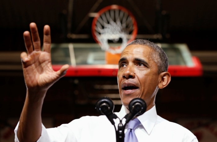 Standing below a basketball hoop, U.S. President Barack Obama speaks about the housing market during a visit to a Phoenix high school January 8, 2015. The Federal Housing Administration will reduce annual mortgage insurance premiums by 0.5 percentage point to 0.85 percent from 1.35 percent, the White House said on Wednesday.