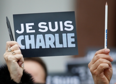 An employee of the Council of Europe holds a placard which read "I am Charlie" and a pen, during a minute of silence in front of the Council of Europe in Strasbourg, January 9, 2015, two days after gunmen stormed weekly satirical newspaper Charlie Hebdo in Paris. The two main suspects in the weekly satirical newspaper Charlie Hebdo killings were sighted on Friday in the northern French town of Dammartin-en-Goele where at least one person had been taken hostage, a police source said.