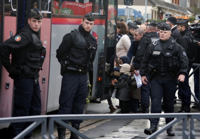 French gendarmes stand guard as school children board a bus as they are evacuated near the scene of a hostage taking at an industrial zone in Dammartin-en-Goele, northeast of Paris January 9, 2015. The two main suspects in the weekly satirical newspaper Charlie Hebdo killings were sighted on Friday in the northern French town of Dammartin-en-Goele where at least one person had been taken hostage, a police source said.