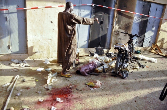 A man stands at the scene of a double suicide bomb attack at the Kantin Kwari textile market in Kano, Nigeria, December 10, 2014. Four people were killed and seven injured when two female suicide bombers attacked the Kantin Kwari textile market in Nigeria's second city Kano on Wednesday, a police commissioner said, less than two weeks after militants attacked its main mosque.