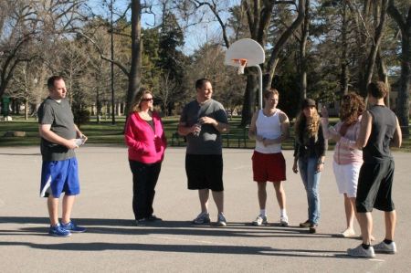 The wives stop by while the men play basketball to give them water.