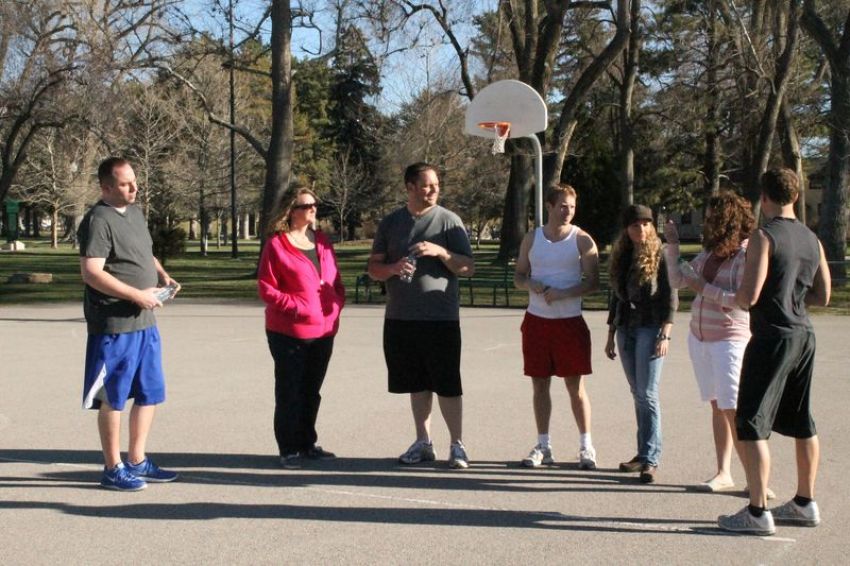 The wives stop by while the men play basketball to give them water.
