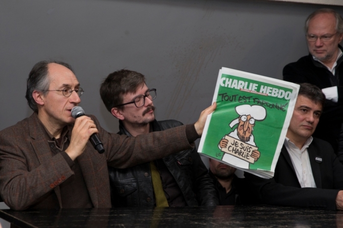 Satirical French magazine Charlie Hebdo new editor in chief Gerard Briard (L) holds a copy of their next issue titled 'Tout est pardonne' ('All is forgiven') showing a caricature of the Muslim prophet Muhammad during a news conference at the French newspaper Liberation offices in Paris, January 13, 2015. Charlie Hebdo will publish the front page showing a caricature of Muhammad holding a sign saying 'Je suis Charlie' in its first edition since Islamist gunmen attacked the satirical newspaper. With demand surging for the edition due on Wednesday, the weekly planned to print up to 3 million copies and in sixteen languages, dwarfing its usual run of 60,000, after newsagents reported that large numbers of customers around the country were placing orders.