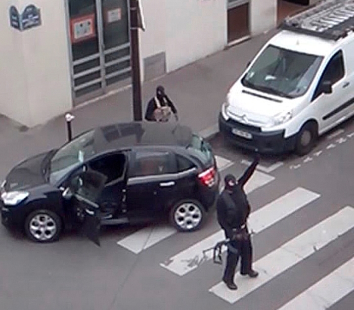 Gunmen gesture as they return to their car after the attack outside the offices of French satirical weekly newspaper Charlie Hebdo (seen at rear) in this still image taken from amateur video shot in Paris, January 7, 2015. Twelve people were slain, including two police officers, during last week's attack by Islamist militants Cherif and Said Kouachi.