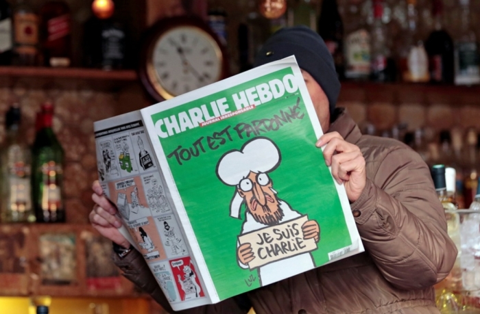 A man poses with the new issue of French satirical weekly Charlie Hebdo entitled 'Tout est pardonne' ('All is forgiven'), which shows a caricature of Muslim prophet Muhammad, at a cafe in Nice, southern France, January 14, 2015. The first edition of Charlie Hebdo published after the deadly attacks by Islamist gunmen sold out within minutes at newspaper kiosks around France on Wednesday, with people queuing up to buy copies to support the satirical weekly. A print run of up to three million copies has been set for what has been called 'the survivors' edition,' dwarfing the usual 60,000 run.