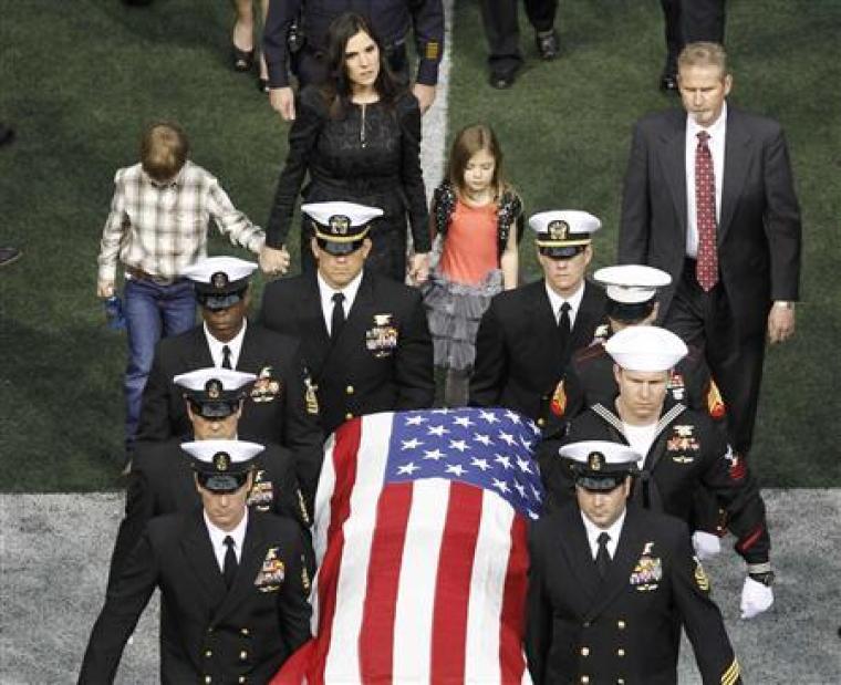 Taya Kyle (rear) and her children walk behind the coffin of her slain husband former Navy SEAL Chris Kyle during a memorial service for the former sniper at Cowboys Stadium in Arlington, Texas, February 11, 2013.