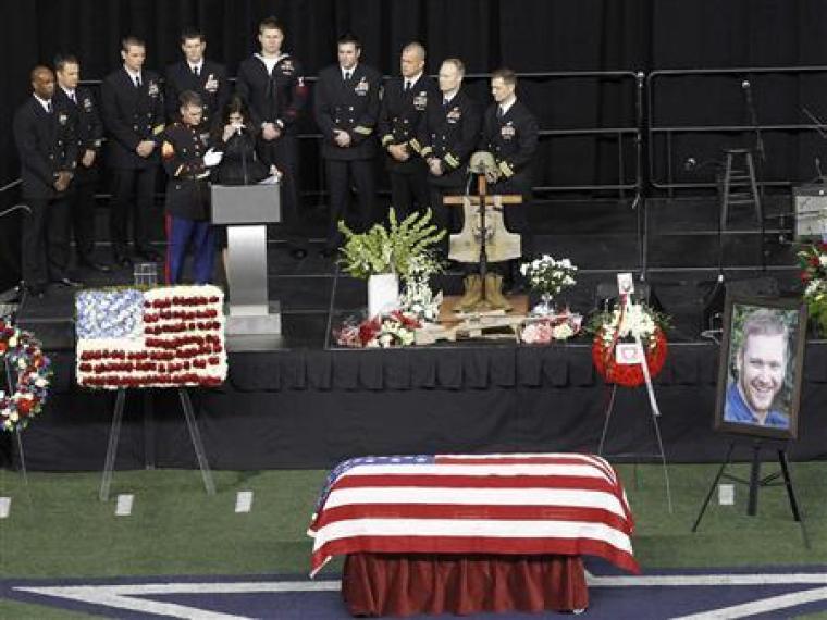 Taya Kyle is steadied by a Marine while addressing friends and family during a memorial service for slain husband and former Navy SEAL sniper Chris Kyle at Cowboys Stadium in Arlington, Texas, February 11, 2013.