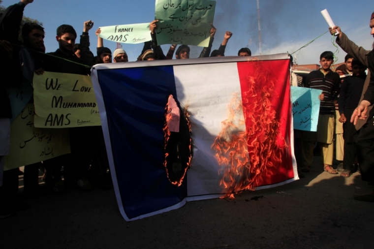 Supporters of the Al Muhammadia religious group hold signs as they burn the French flag during a protest against satirical French weekly newspaper Charlie Hebdo, which featured a cartoon of the Muslim prophet Muhammad as the cover of its first edition since an attack by Islamist gunmen, in Peshawar, Pakistan, January 19, 2015.