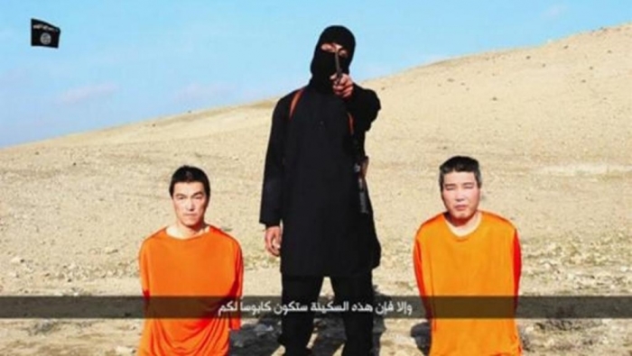 A masked person holding a knife speaks as he stands in between two kneeling men in this still image taken from an online video released by the militant Islamic State group on January 20, 2015.
