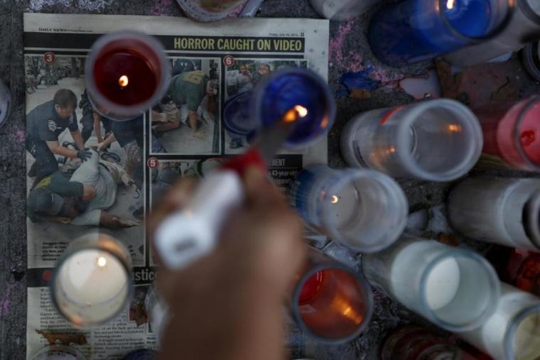 A woman pays respect with a candle at the memorial of Eric Garner in Staten Island, New York, July 21, 2014.