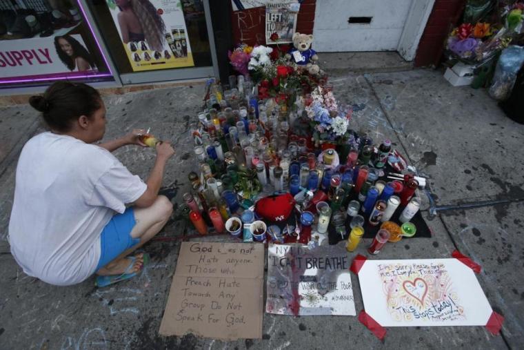 A woman pays respect with a candle at the memorial of Eric Garner in Staten Island, New York, July 21, 2014.