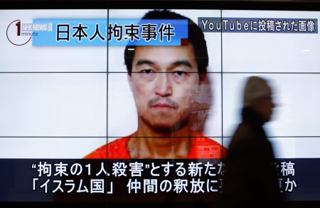 A man walks past screens displaying a television news programme showing an image of Kenji Goto, one of two Japanese citizens taken captive by Islamic State militants, on a street in Tokyo January 25, 2015. Japanese Prime Minister Shinzo Abe on Sunday called the apparent killing of Japanese captive Haruna Yukawa by Islamic State militants "outrageous and impermissible," and again called for the group to release Goto, the second Japanese national they are holding. The words on the screen read "Japanese hostage incident" (top L) and "a still image posted on YouTube" (top R).