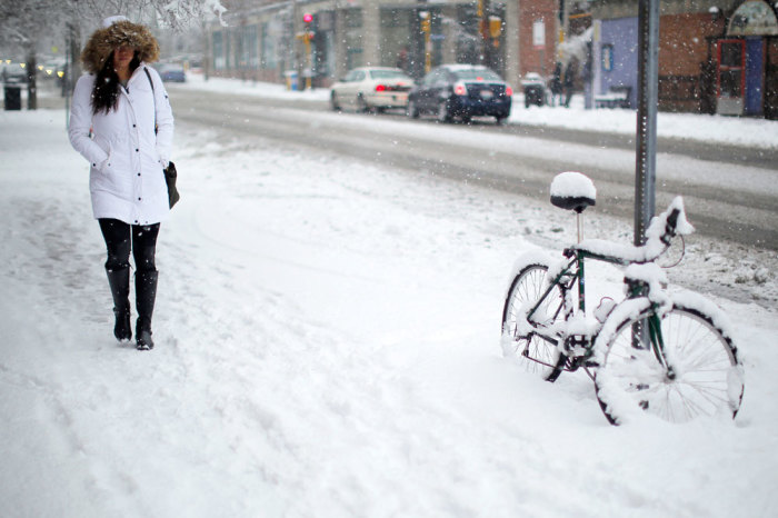 A woman walks past a bicycle covered in snow during a winter snowstorm in Cambridge, Massachusetts January 24, 2015. Up to 8 inches of snow is expected to fall over parts of the Northeast this weekend, and a wintry mix could make for a messy Monday morning commute in New York, Boston and other cities, the National Weather Service said on Friday.