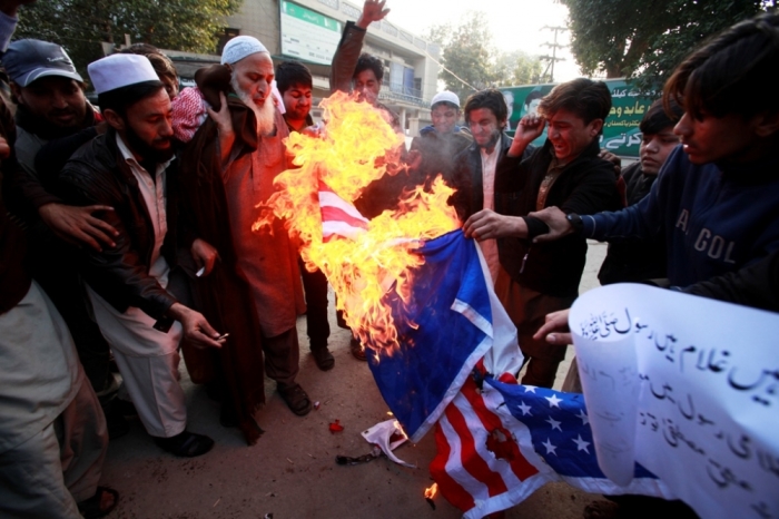 Supporters of the religious party Jamiat-e-Ulema Islam burn a U.S. flag during a protest against against satirical French weekly newspaper Charlie Hebdo, which featured a cartoon of the Islamic prophet Muhammad as the cover of its first edition since an attack by Islamist gunmen, in Lahore, Pakistan, January 23, 2015.