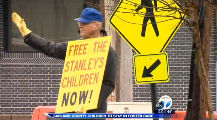 A family friend of the Stanley family holds up a sign calling for their seven kids to be returned home after they were taken into state custody in January of 2015.