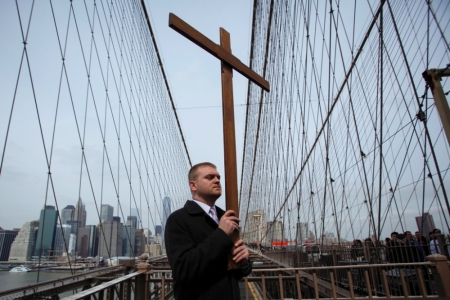 Jonathan Fromm, New York member of Communion and Liberation, carries a cross on the Brooklyn Bridge during the 19th annual 