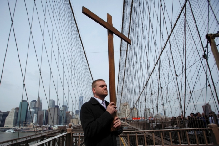 Jonathan Fromm, New York member of Communion and Liberation, carries a cross on the Brooklyn Bridge during the 19th annual 'Way of the Cross Over the Brooklyn Bridge Ceremony' in New York City, April 18, 2014. The ceremony, hosted yearly on the Christian holy day of Good Friday, includes walking from St. James Cathedral, over the Brooklyn Bridge to St. Peter's Church in Manhattan. The event attracts approximately 2,000 people each year.