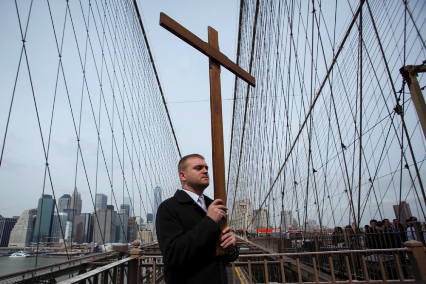 Jonathan Fromm, New York member of Communion and Liberation, carries a cross on the Brooklyn Bridge during the 19th annual 