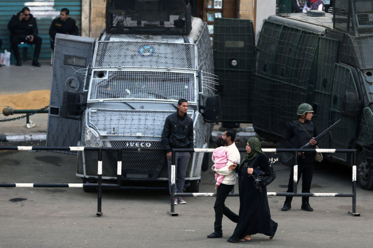 People walk past police standing guard in central Cairo, January 27, 2015.