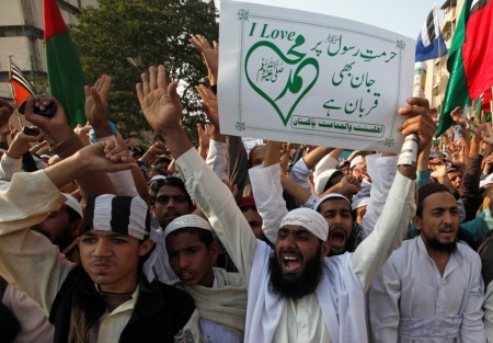 Supporters of Ahl-i-Sunnat Wal Jamaat, a political and religious group, chant slogans as they carry a sign during a protest against satirical French weekly newspaper Charlie Hebdo, which featured a cartoon of the Muslim prophet Muhammad as the cover of its first edition since an attack by Islamist gunmen, in Karachi, Pakistan, January 23, 2015. The sign reads in Urdu: 