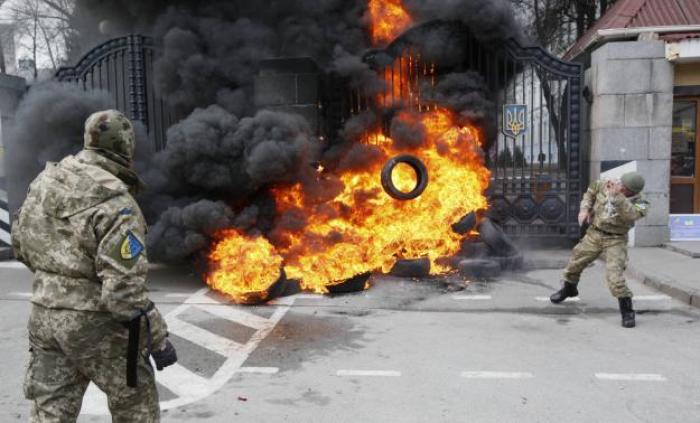 A serviceman from the battalion 'Aydar' throws a tyre on a fire during a protest against disbanding of the battalion in front of Ukraine's Defence Ministry in Kiev, February 2, 2015.