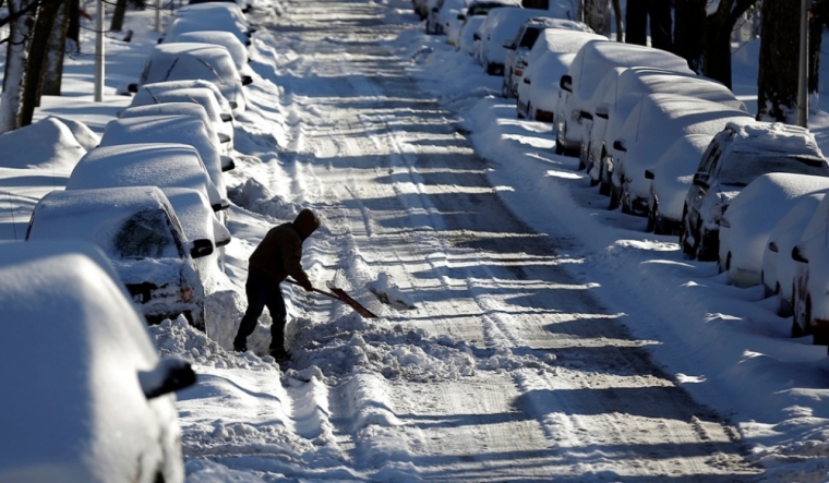 A man digs a car out of the snow on a residential street in the Chicago suburb of Evanston, Illinois, February 2, 2015. A huge winter storm hit the northeastern United States on Monday, the region's second snowy blast in less than a week, after leaving more than a foot of snow in the Chicago area. The area was hit with blizzard conditions yesterday and the temperature dropped to well below freezing.