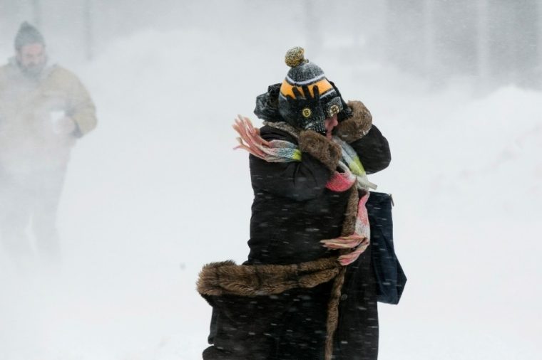 A woman holds onto her hat against the wind during a snow storm in Boston, Massachusetts, February 2, 2015. Boston, already buried under two feet of snow from a blizzard last week, was predicted to see a foot of snow after a huge winter storm hit the northeastern United States on Monday, the region's second snowy blast in less than a week.