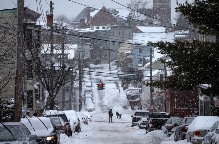 People walk on a snow covered street as snow falls in Tarrytown village, Westchester County, New York, February 2, 2015. A huge winter storm hit the northeastern United States on Monday, the region's second snowy blast in less than a week, after leaving more than a foot of snow in the Chicago area. Up to six inches of snow was forecast for New York City, where the snow and ice caused a crowded subway train to stall on an elevated stretch of track.