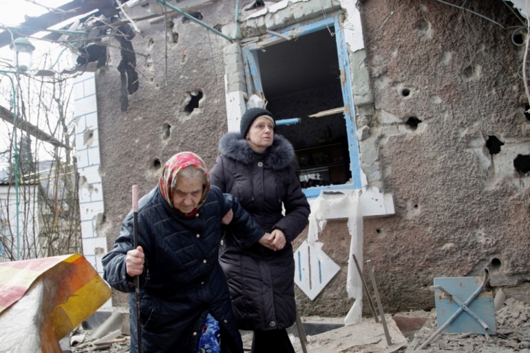 People walk outside a house, which according to locals was recently damaged by shelling, in Donetsk, Ukraine, February 3, 2015.