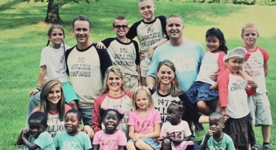 Suzanne Mayernick and Gwen Oatsvall are pictured here with their husbands Mike and Scott and their 13 children, seven of whom are adopted.