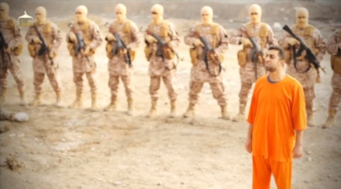 A man purported to be Islamic State captive Jordanian pilot Muath al-Kasaesbeh (in orange jumpsuit) stands in front of armed men in this still image from an undated video filmed from an undisclosed location made available on social media on February 3, 2015. Islamic State militants released the video on Tuesday purporting to show Kasaesbeh being burnt alive, and Jordanian state television said he was murdered a month ago. Reuters could not immediately confirm the video, which showed a man resembling the captive pilot standing in a black cage before being set ablaze.