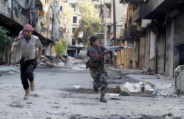 Mohammad (R), a 13 year-old fighter from the Free Syrian Army, aims his weapon as he runs from snipers loyal to the Syrian regime in Aleppo's Bustan al-Basha district, October 29, 2013. Mohammad joined the Free Syrian Army after his father died during clashes with the Syrian regime. The gun he is using was his father's.