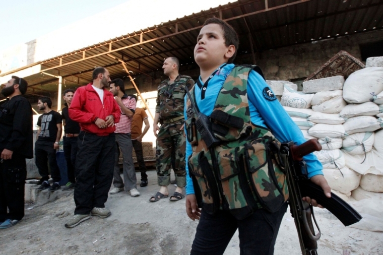 Abboud, 12, stands with his weapon beside fellow Free Syrian Army fighters in Aleppo's Sheikh Saeed neighbourhood, September 28, 2013. Abboud and his brother Deeb, 14, both school-going children before the civil war, joined the Free Syrian Army after the deaths of two of their brothers and an uncle in the conflict.