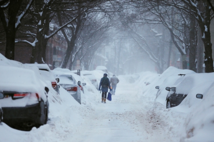 Pedestrians make their way along a snow covered street during a winter snow storm in Cambridge, Massachusetts, February 9, 2015. Boston and other areas of the Northeast, already buried under about a yard of snow, braced for up to two more feet through early Tuesday while more rain and high winds were in store for parts of the Pacific coast, forecasters said on Sunday.