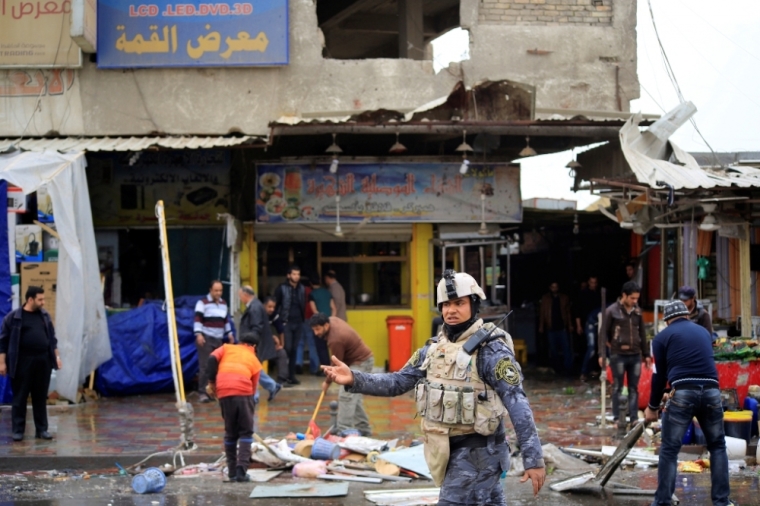 A member of the Iraqi security forces walks past the site of a bomb attack in Baghdad, Iraq, February 7, 2015. At least 34 people were killed in three bombings around Baghdad on Saturday, police said, hours before the government was due to lift a long-standing night-time curfew on the capital. At least 50 people were wounded in the blasts, the officials said.