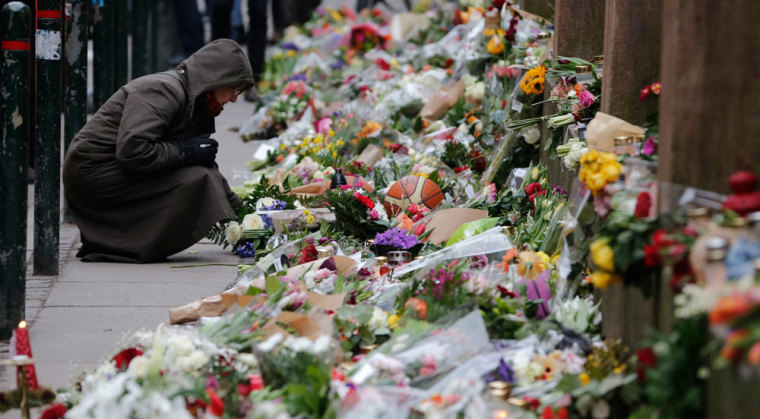 A woman lays down a flower at a memorial for the victims of the deadly attacks in front of the synagogue in Krystalgade in Copenhagen, February 16, 2015. The shootings, which Prime Minister Helle Thorning-Schmidt called acts of terrorism, sent shockwaves through Denmark and have been compared to the January attacks in Paris by Islamist militants that killed 17.