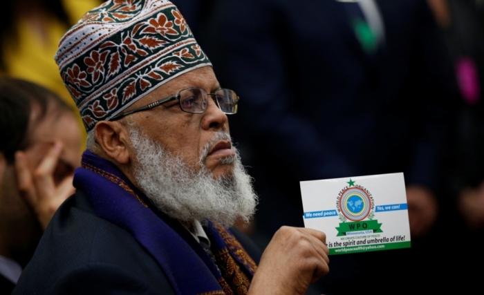 Imam Sheikh Sa'ad Musse Roble of Minneapolis, Minnesota, holds up a card from the WPO World Peace Organization as he listens to U.S. President Barack Obama during his speech before the White House Summit on Countering Violent Extremism in Washington, February 18, 2015.