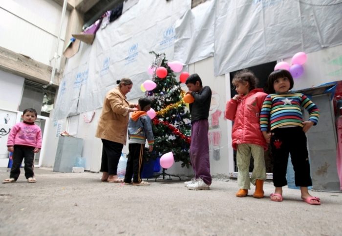 Displaced Iraqi Christian children who fled from Islamic State militants in Mosul, gather around a Christmas tree at a mall still under construction, used as a refugee camp in Erbil, December 24, 2014.