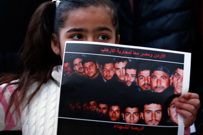 A girl holds up a poster with pictures of the 21 Egyptian Coptic Christians beheaded by Islamic State in Libya, as they gather in a gesture to show their solidarity, in front of the Egyptian embassy in Amman February 17, 2015.