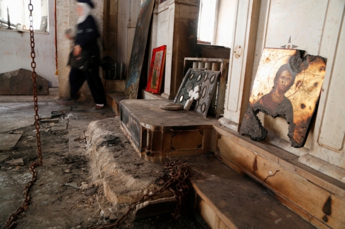 A woman walks inside a damaged church in Maaloula, August 21, 2014. Residents of Maaloula, a Christian town in Syria, call on other Christian groups and minorities to stand up to the radicalism that is sweeping across Syria and Iraq. The town was regained by Syrian Army forces in April 2014 from Islamic militants, and several months later life is slowly returning to the town.