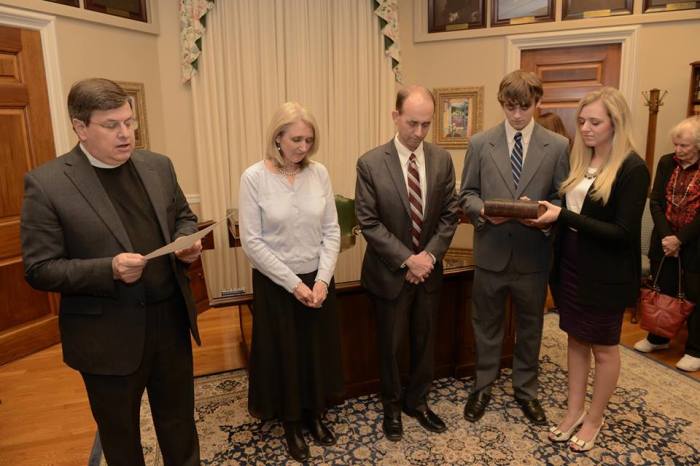 Tom Schweich, Missouri's Republican state auditor (center) pauses for a moment of prayer with his family before his swearing for a second term in the position in January.