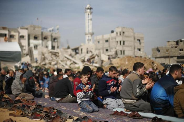 Palestinians attend Friday prayers near the ruins of houses that witnesses said were destroyed or damaged by Israeli shelling during a 50-day war last summer, in the Shejaia neighbourhood east of Gaza City, January 23, 2015.