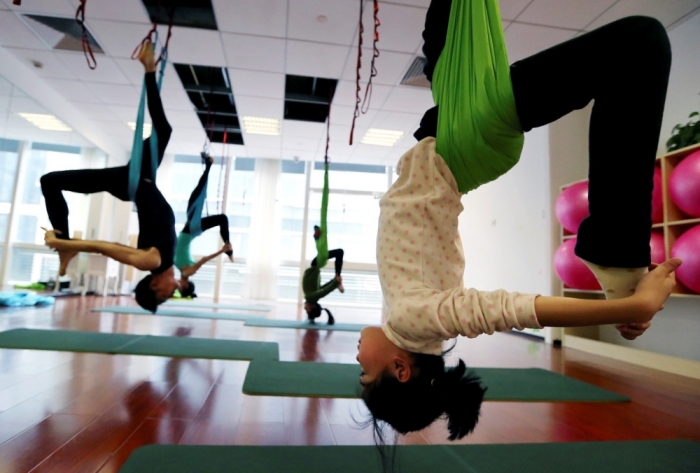 Students practice antigravity yoga at a training room in Hangzhou, Zhejiang province, January 11, 2015. The use of hammocks help practicers to release pressure from their spines and reshape their bodies, according to local media reports.