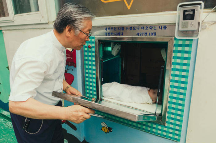 Pastor Lee Jong-rak looks at a baby in his drop box.