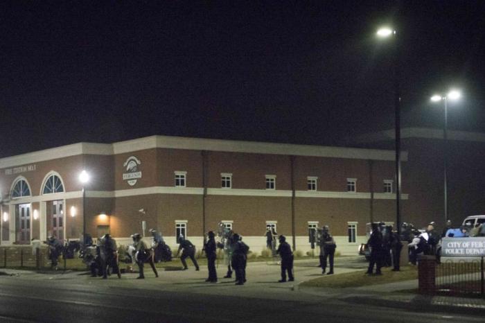 Police stand guard moments after gun shots were fired outside the City of Ferguson Police Department and Municipal Court in Ferguson, Missouri, early March 12, 2015.