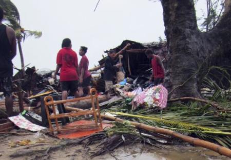 Local residents look through the remains of a small shelter in Port Vila, the capital city of the Pacific island nation of Vanuatu, March 14, 2015.
