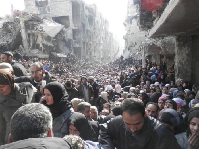 Residents of Yarmouk refugee camp in the southern district of Damascus wait in line to received food rations given out by the United Nations Relief and Works Agency.