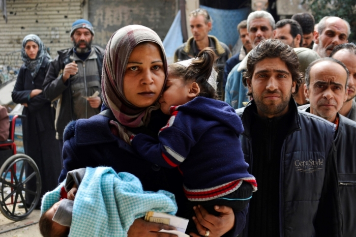 Residents queue up to receive humanitarian aid at the Palestinian refugee camp of Yarmouk, in Damascus March 11, 2015. The Palestinian Yarmouk refugee camp in Damascus, which is under siege by Syrian government forces fighting rebels, has received its first relief supplies since the beginning of December. The aid was delivered by the United Nations Relief and Works Organization UNRWA on March 5.