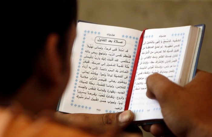 An Egyptian Christian reads an Arabic prayer book during Sunday mass at Saint Mary Church in the heavily populated area of Imbaba in Cairo, June 17, 2012.